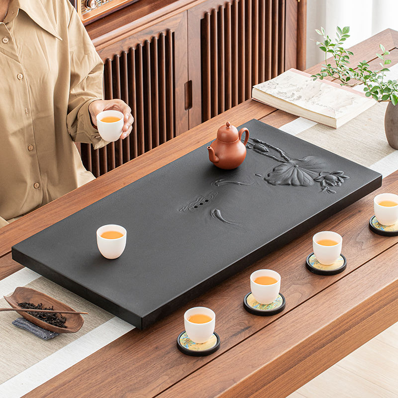 Close-up of fish and lotus engraving on black stone tea tray