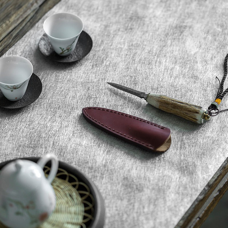 Close-up of handcrafted poplar wood tea knife with leather case for prying compressed tea