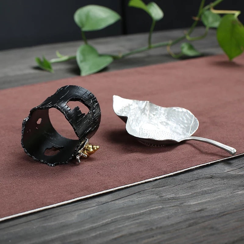 Stylish tea accessories, including a tea infuser with holder, on a tea table