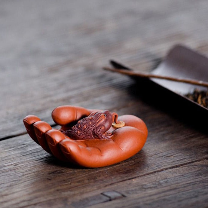 Yixing clay toad tea pet sitting on a traditional tea tray, showcasing intricate craftsmanship