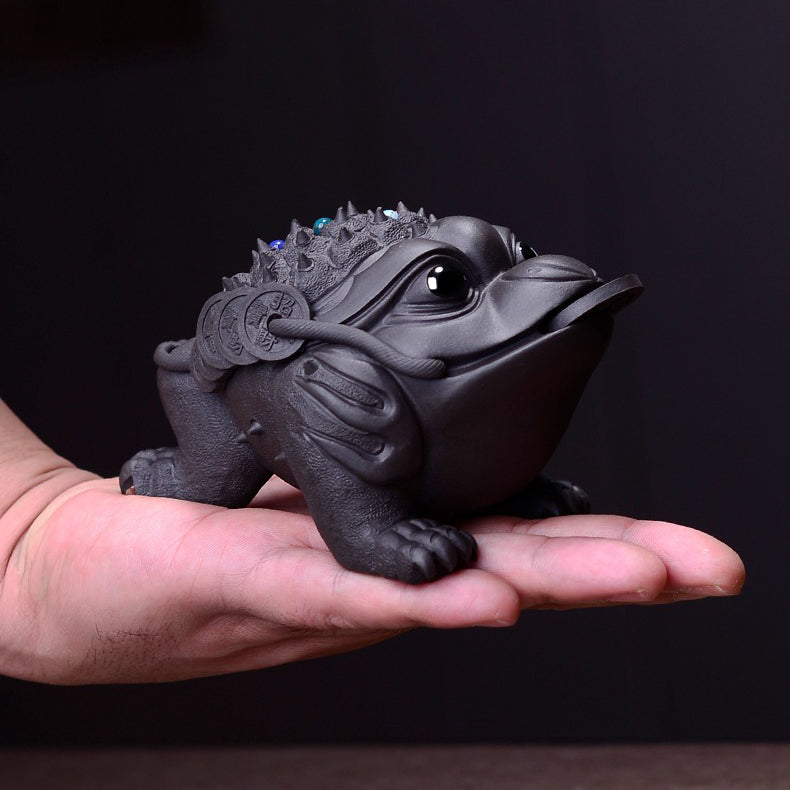Yixing clay toad tea pet sitting on a traditional tea tray, showcasing intricate craftsmanship