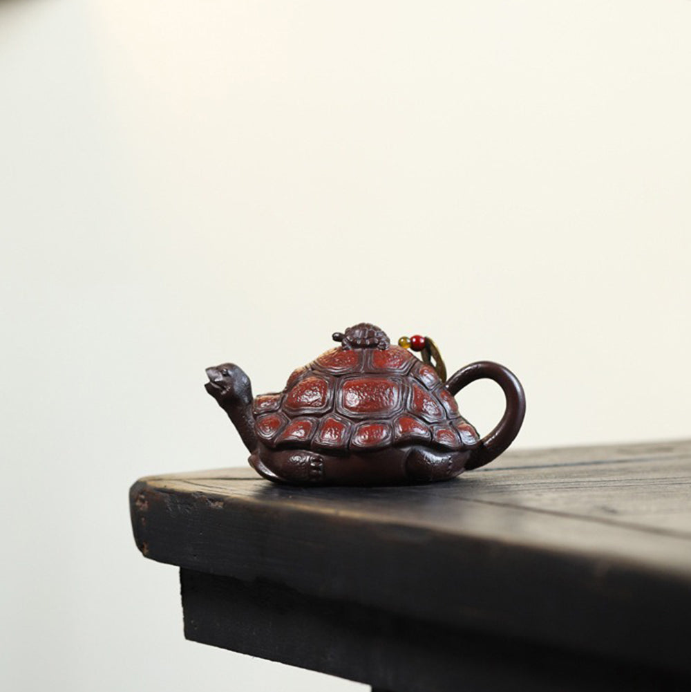 Purple clay turtle teapot displayed on a shelf for elegant home decoration