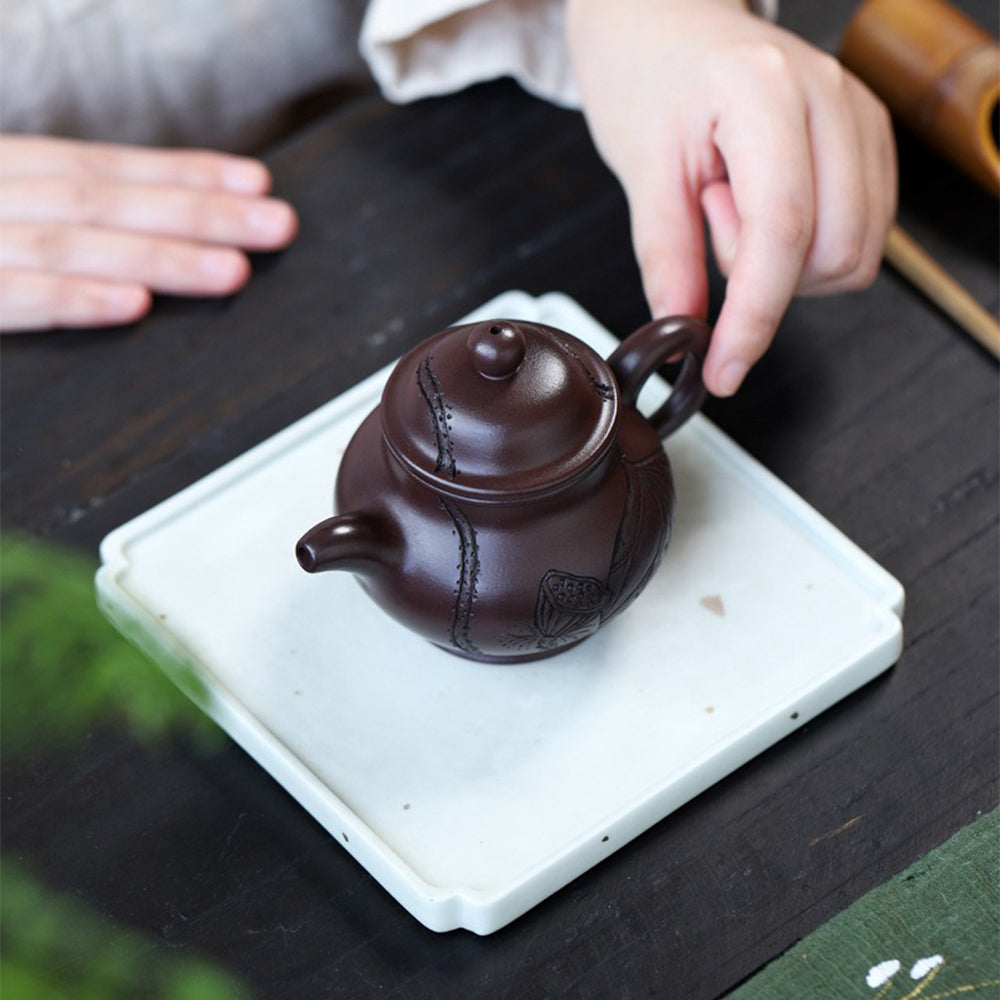 Yixing lotus teapot from an angled view, highlighting its elegant shape and lotus pattern.