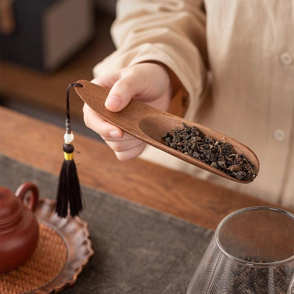 A close-up of the tea knife and teaspoon with copper details displayed on a walnut tray.
