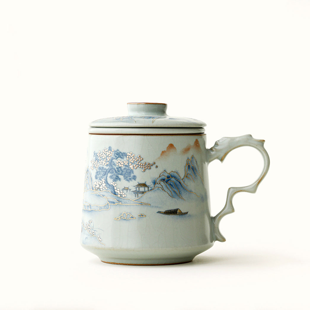 Close-up of the elegant Ruyao landscape tea cup with infuser showing the crackle glaze and gilded mountain outlines