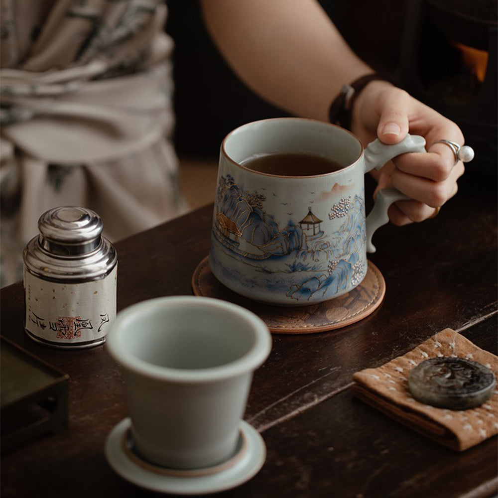 Close-up of the elegant Ruyao landscape tea cup with infuser showing the crackle glaze and gilded mountain outlines
