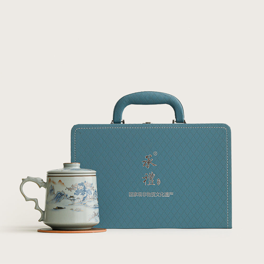 Close-up of the elegant Ruyao landscape tea cup with infuser showing the crackle glaze and gilded mountain outlines