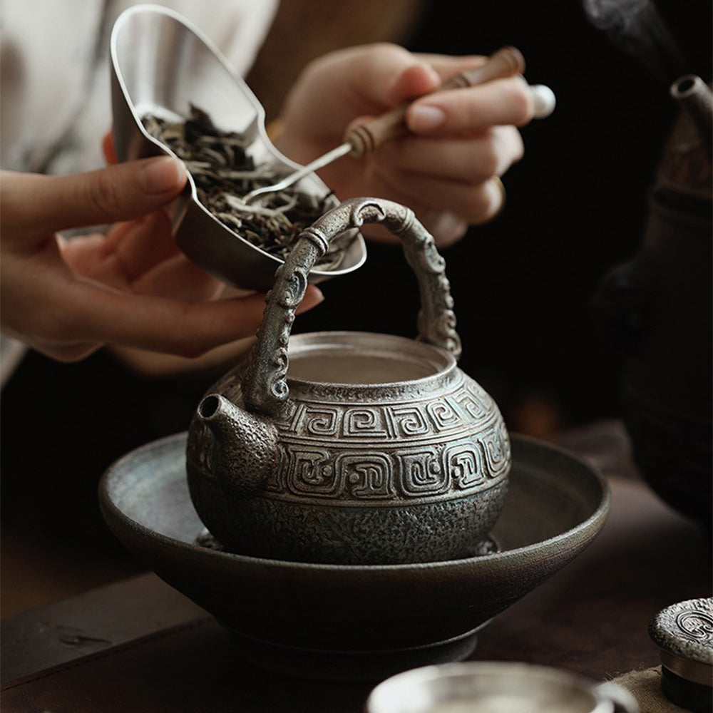 Tea being poured from a silver-plated ceramic teapot onto a cup, highlighting its elegant spout and handle