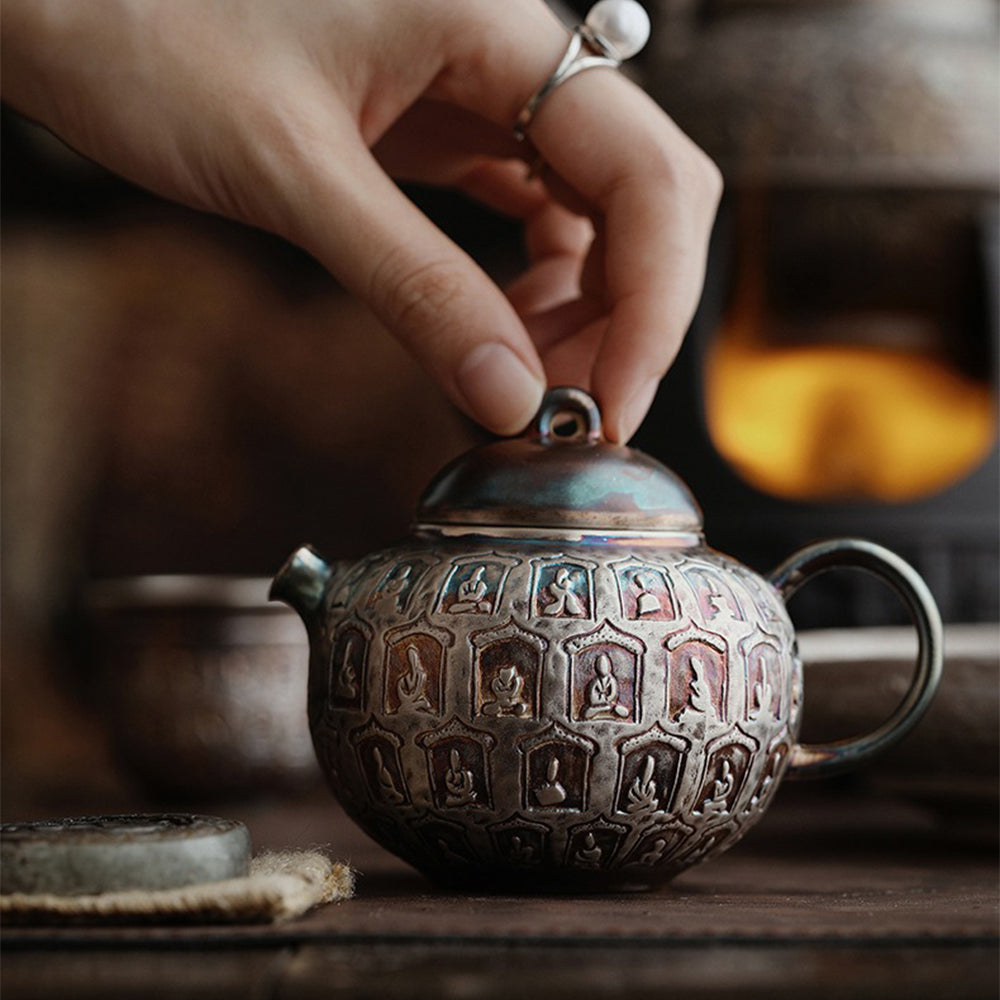 Close-up view of the artistic silver-plated Buddha teapot, highlighting intricate carvings.