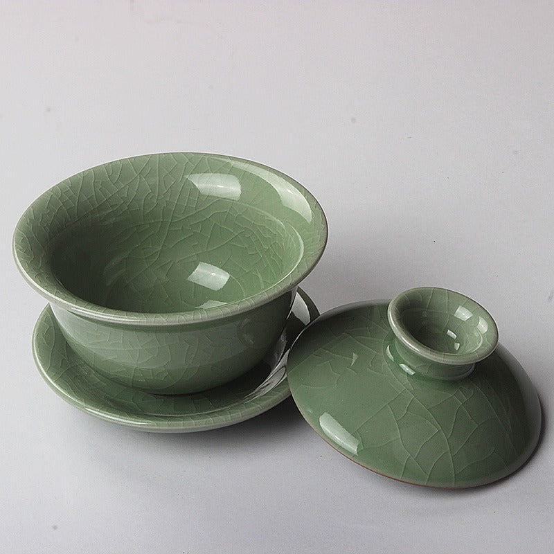 Artisan Longquan gaiwan held over tea tray with steam rising