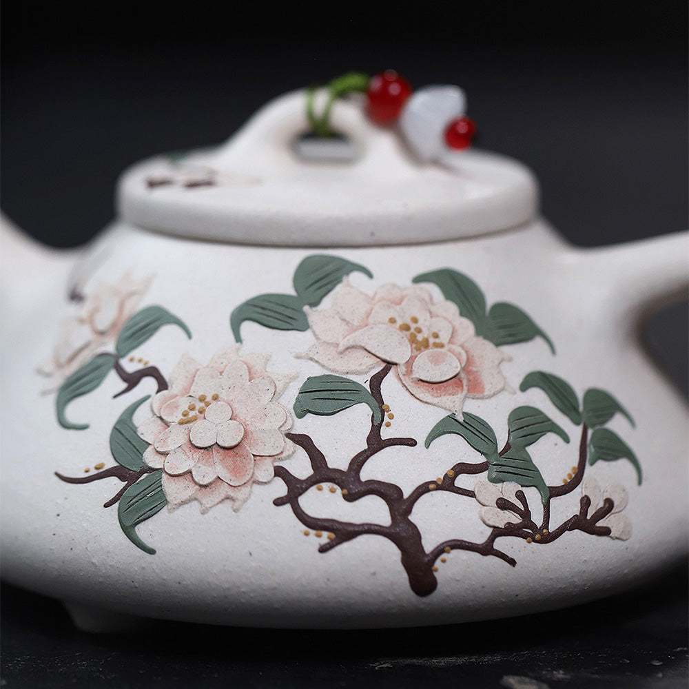 White clay teapot with peony design on a tea table, ready for brewing