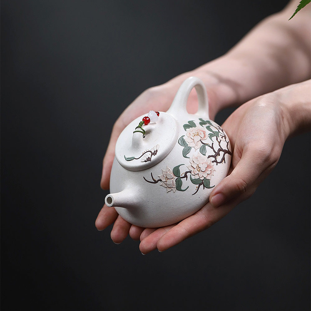 White clay teapot with peony design on a tea table, ready for brewing