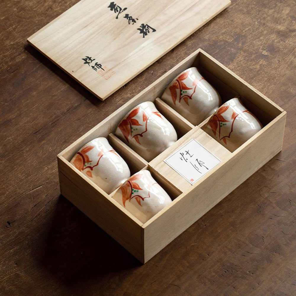 Elegant Japanese ceramic tea cup set with unique designs, displayed in a wooden gift box.