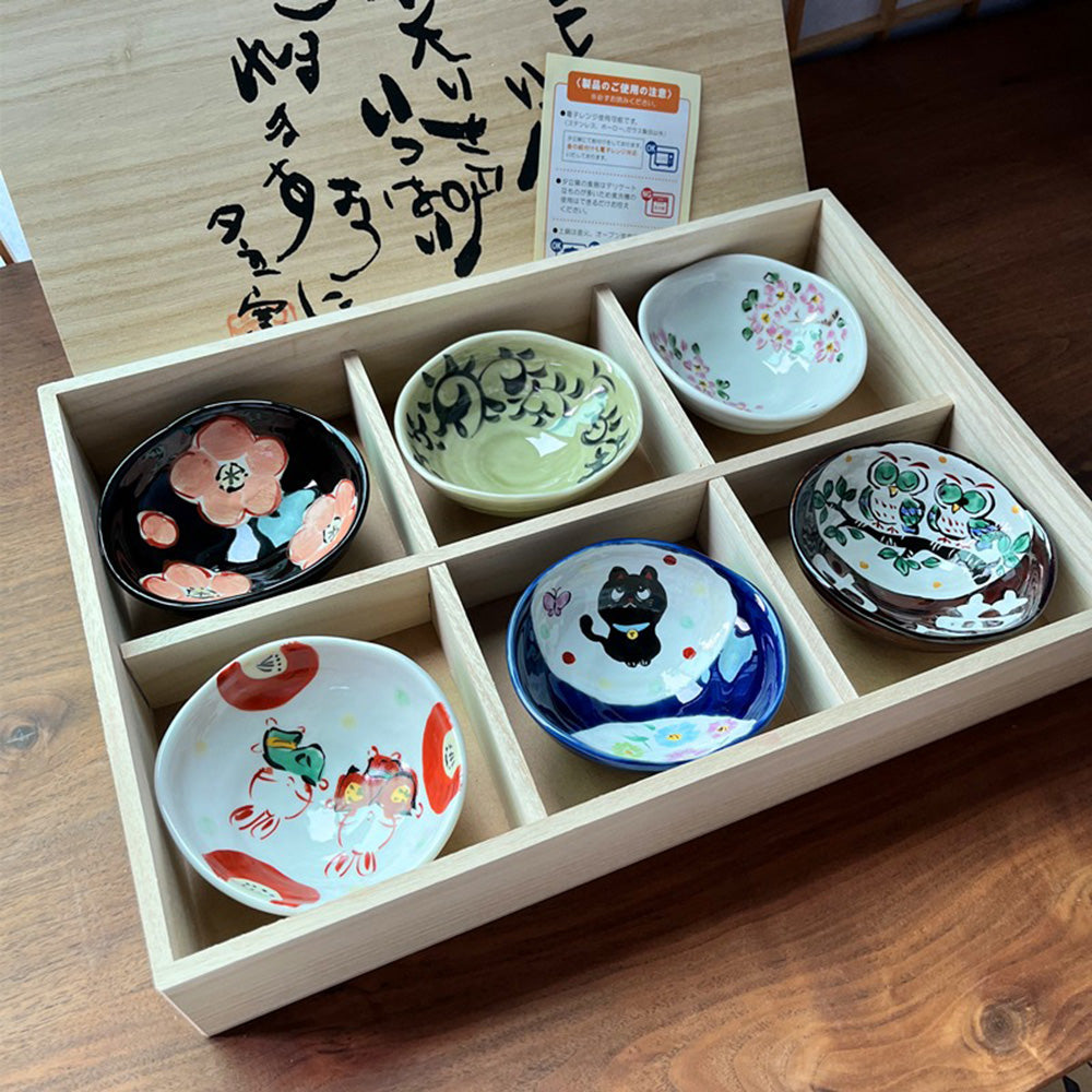 Set of six ceramic mini bowls arranged aesthetically in their wooden box.