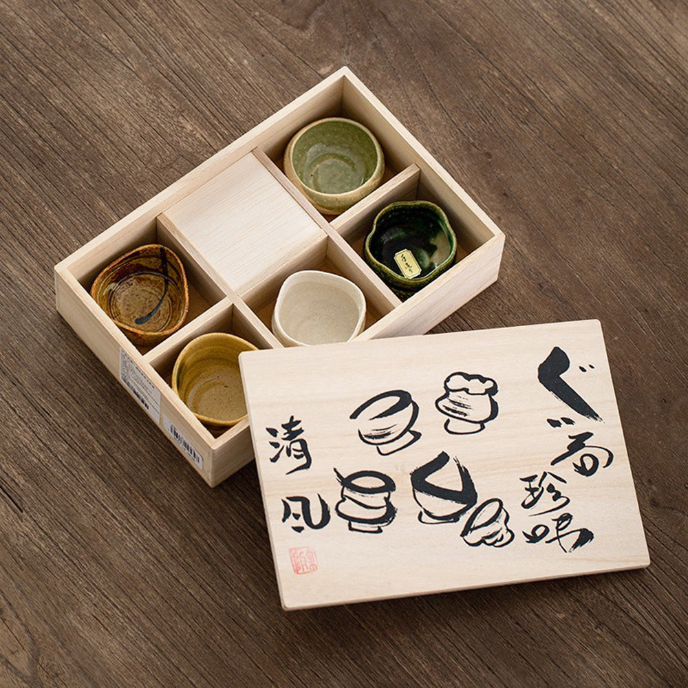A rustic Mino-yaki teacup set displayed with a wooden box, showcasing unique patterns.