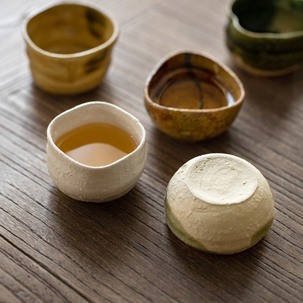 A rustic Mino-yaki teacup set displayed with a wooden box, showcasing unique patterns.