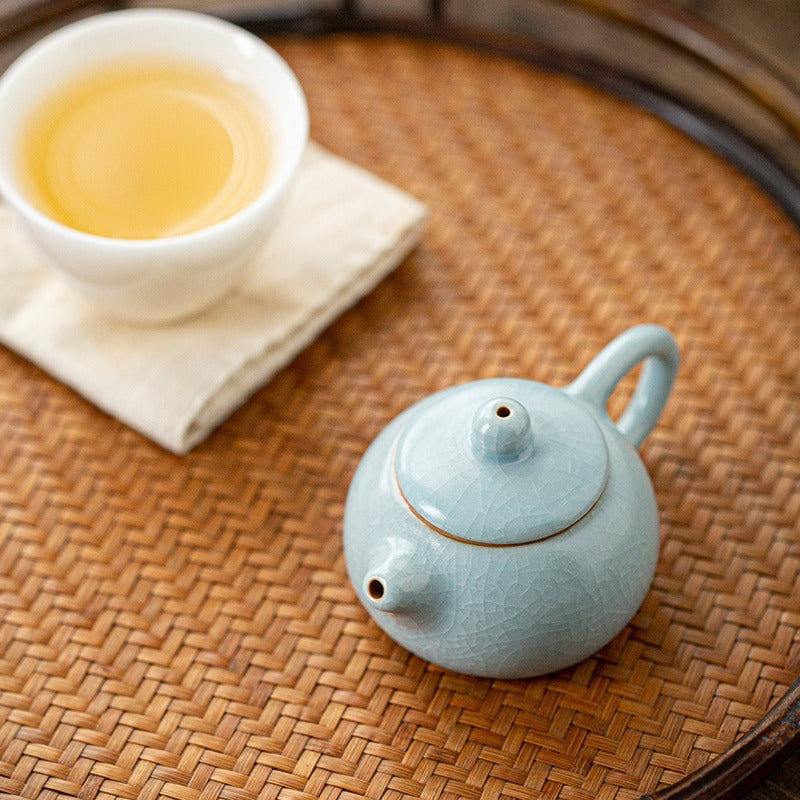 Mini teapot placed beside tea pet figurines, highlighting its collectible charm