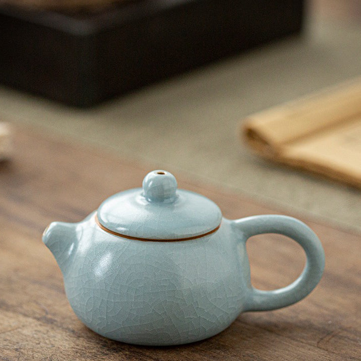 Mini teapot placed beside tea pet figurines, highlighting its collectible charm