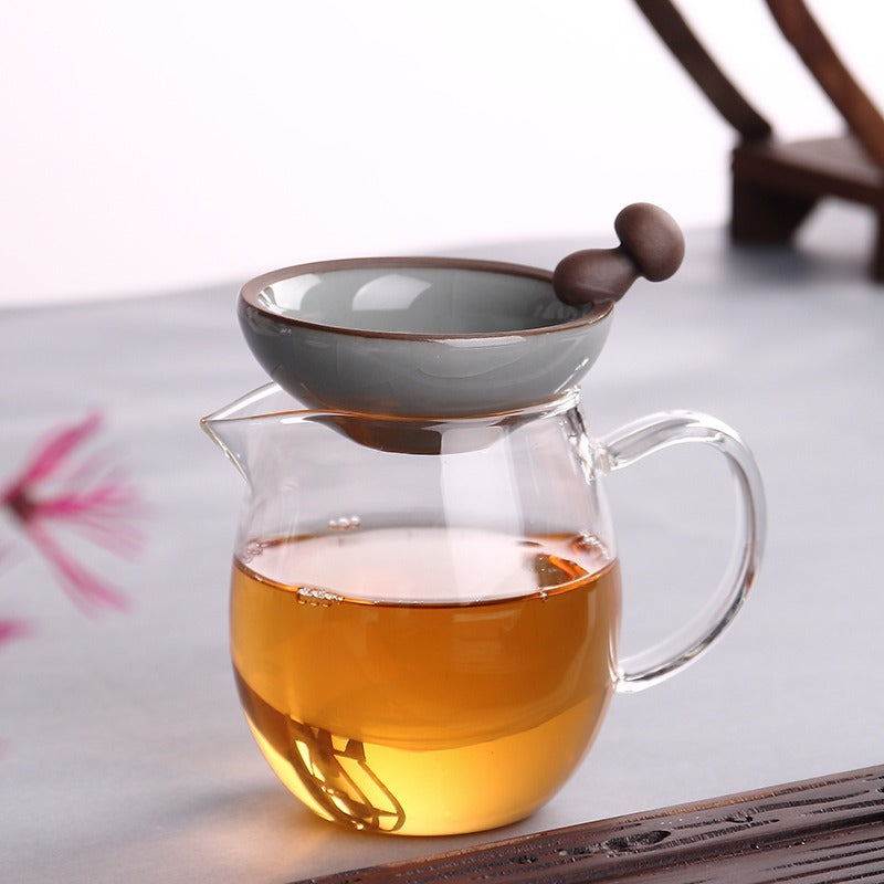 Tea infuser being used to pour brewed loose leaf tea into a cup