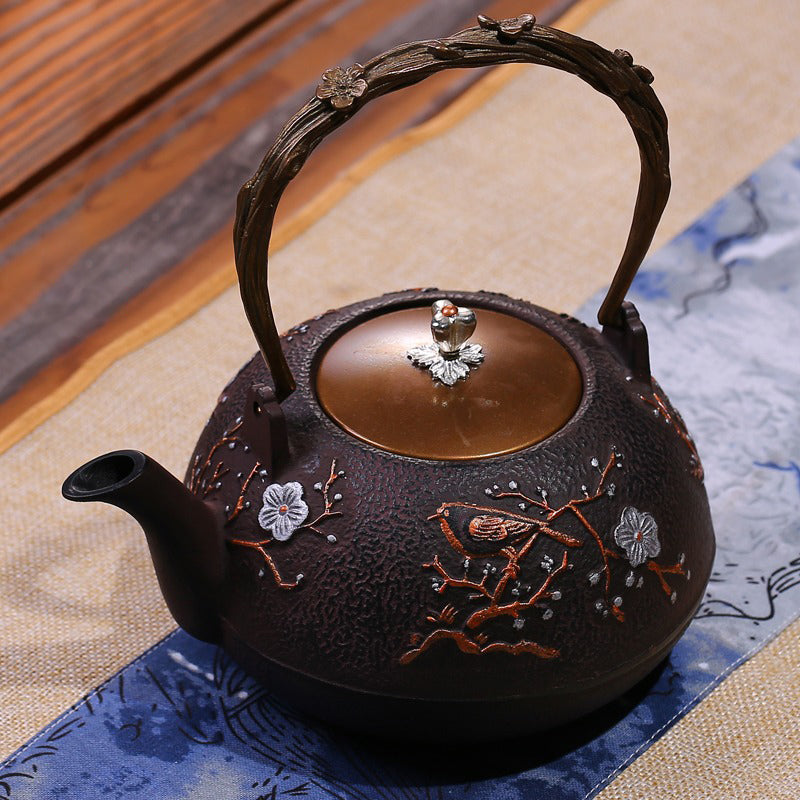 Side view of the Japanese cast iron teapot demonstrating its elegant arc spout and decorative plum blossom detail.