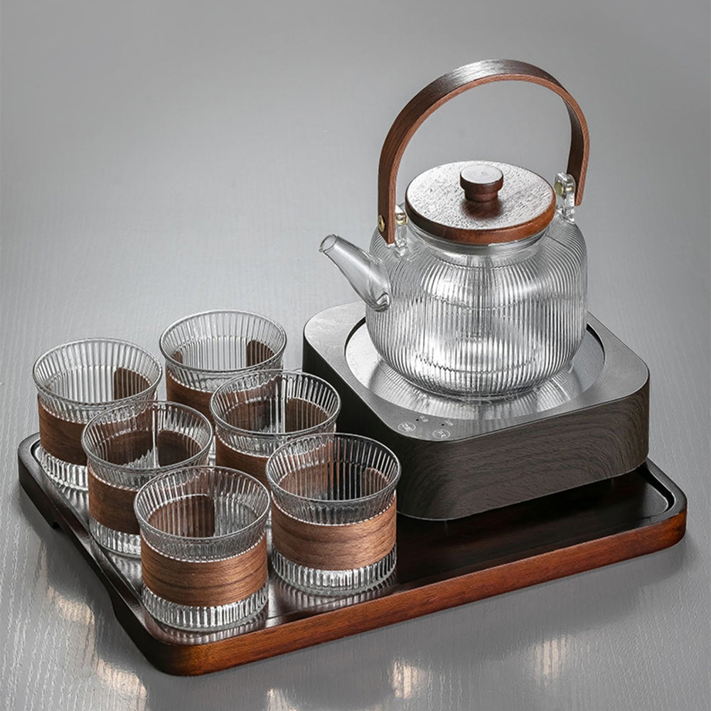Top-down view of the glass gongfu tea set arranged on the wooden tray, highlighting the induction heater and elegant cup design.