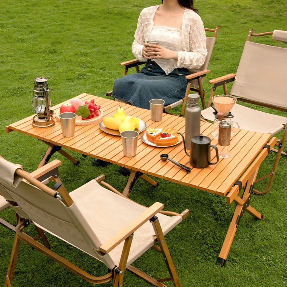 Portable outdoor folding table set with chairs in a natural setting.