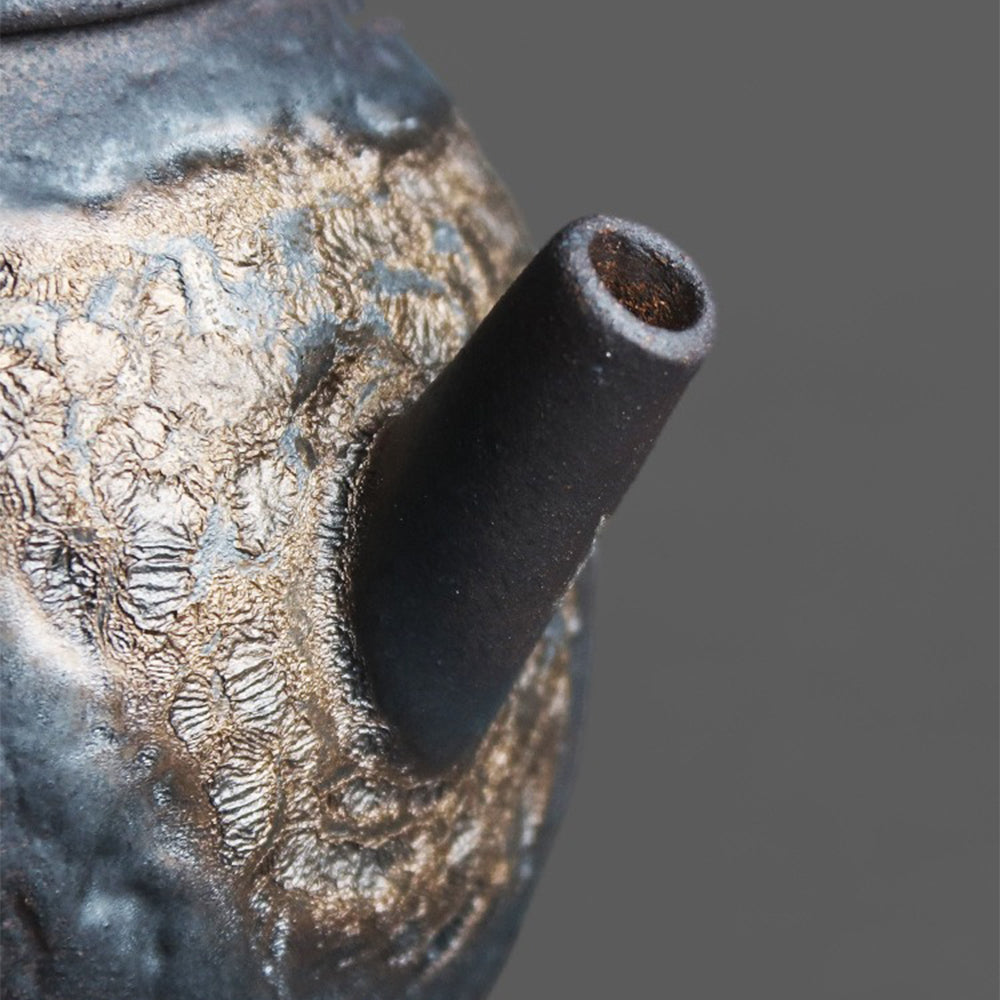 Side view of the purple clay Yixing teapot showing its hammered stone texture and gilded glaze