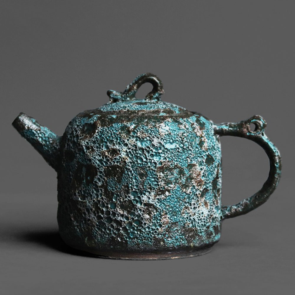 Close-up of the vintage bronze teapot showcasing its unique wormhole design