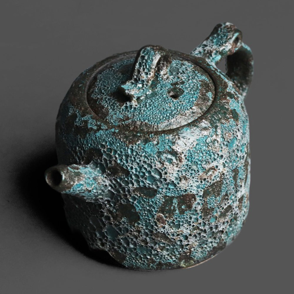 Vintage bronze teapot displayed elegantly with tea leaves and cups