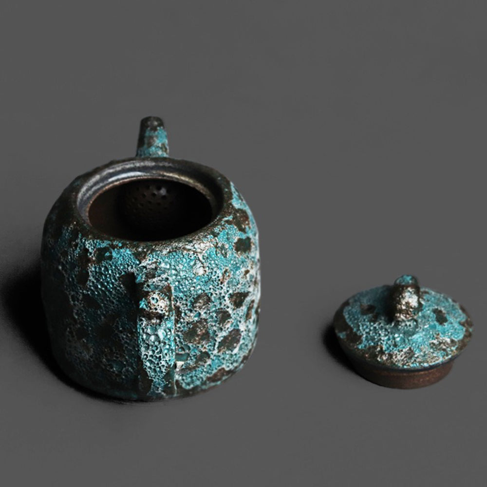 Close-up of the vintage bronze teapot showcasing its unique wormhole design