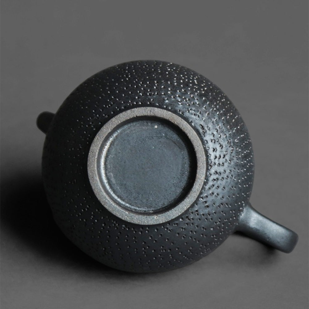 Tea being poured from a black clay teapot into a cup, highlighting its elegant design