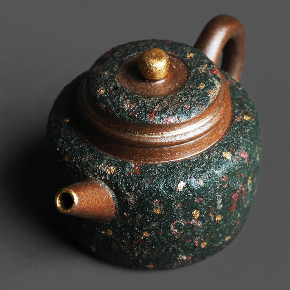 Handheld teapot with gold speckles in use, pouring tea