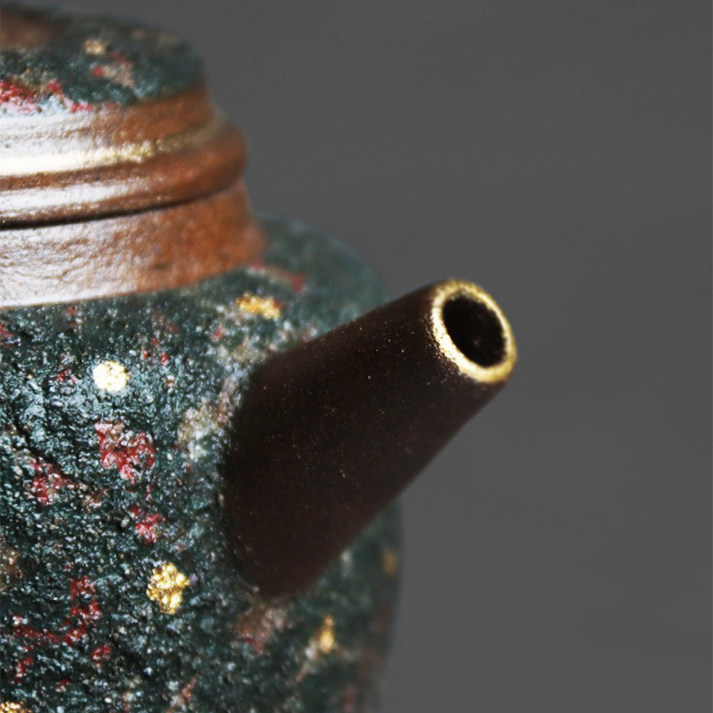 Handheld teapot with gold speckles in use, pouring tea
