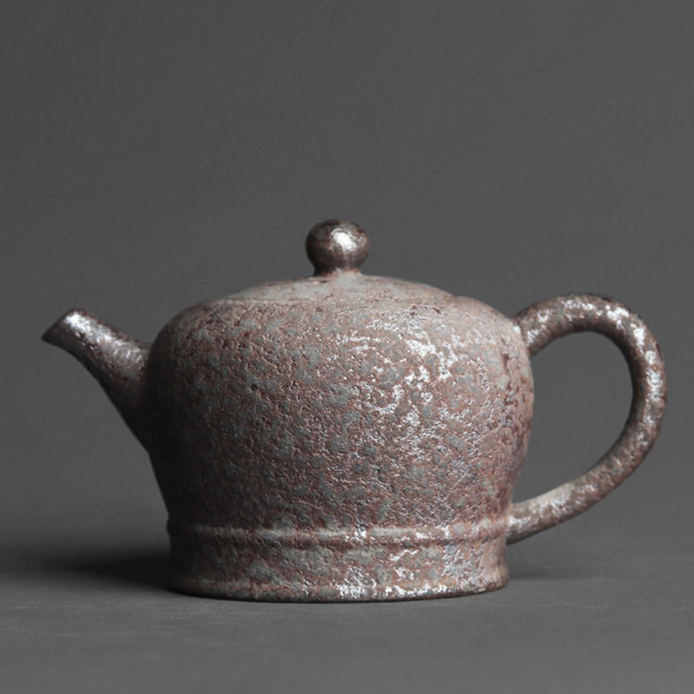 Side view of handmade vintage wood-fired clay teapot with rust spots