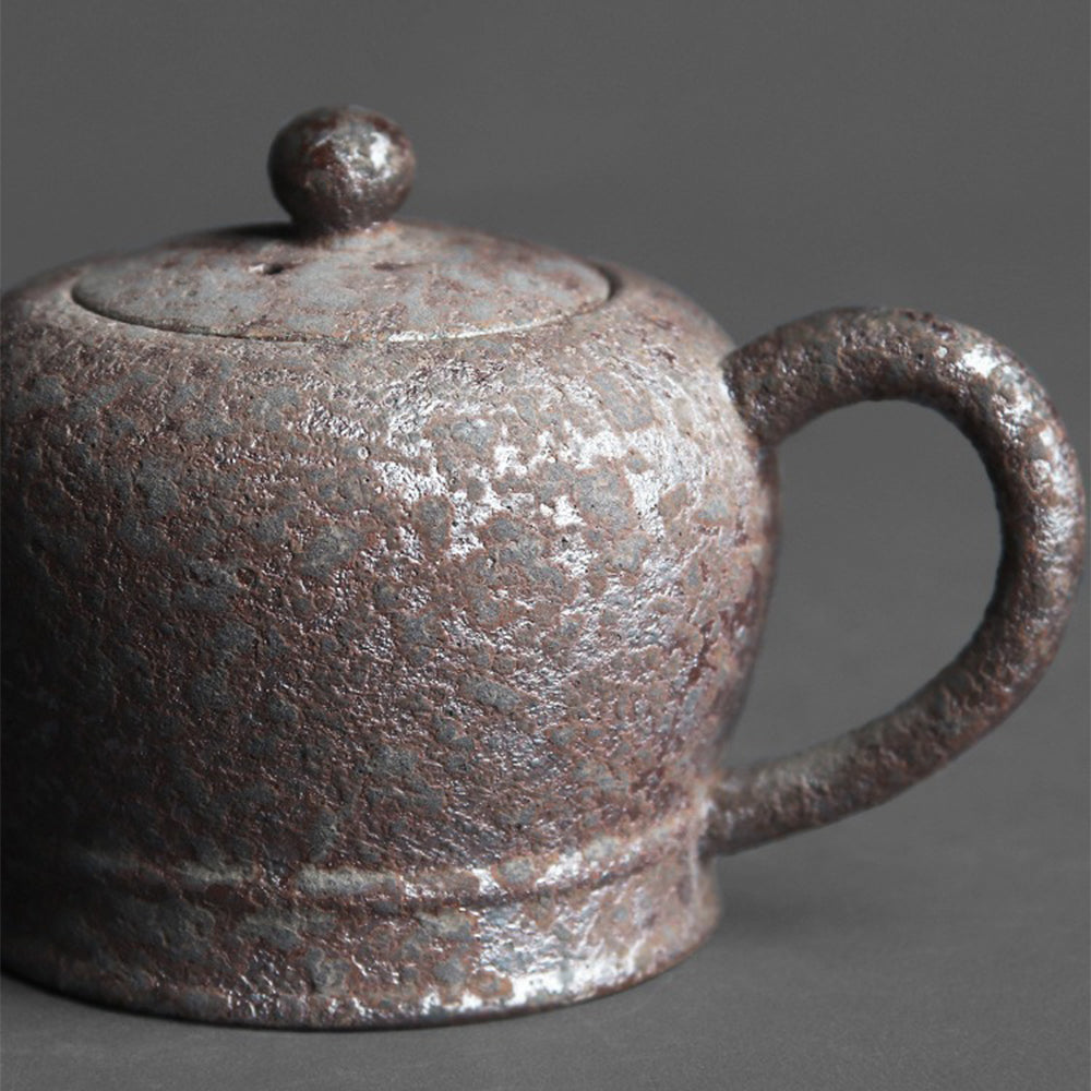 Side view of handmade vintage wood-fired clay teapot with rust spots
