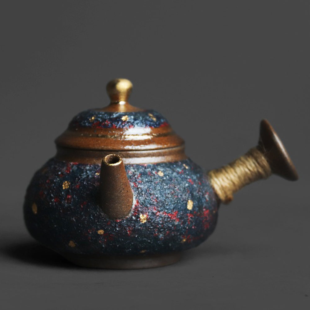 Close-up of the indigo Japanese teapot showcasing its coarse pottery texture and gold accents.