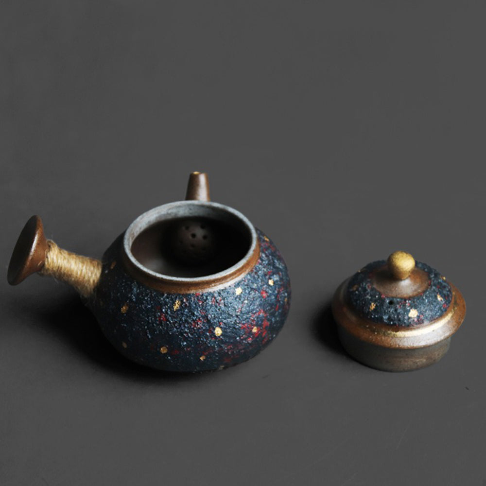 Close-up of the indigo Japanese teapot showcasing its coarse pottery texture and gold accents.