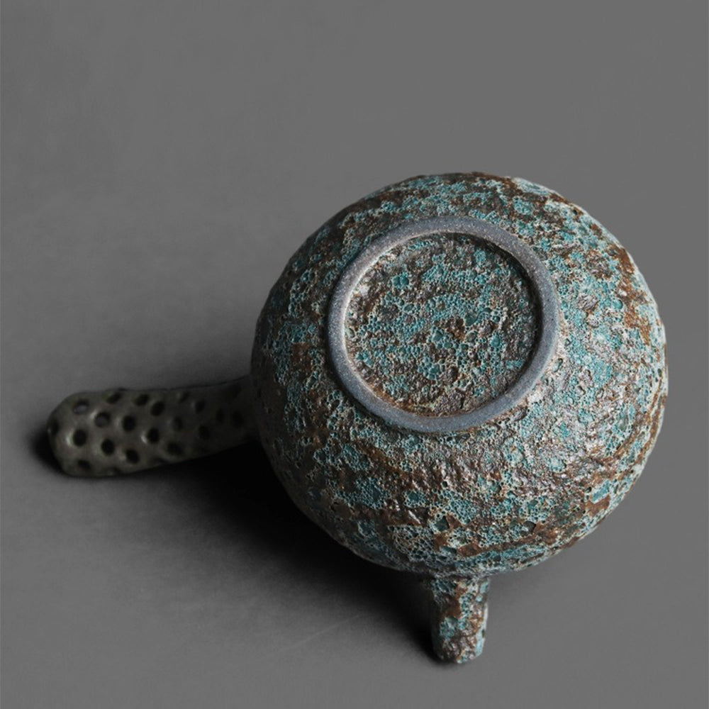 Close-up of the Wormhole Bronze Kyusu Teapots green glaze and metallic texture.