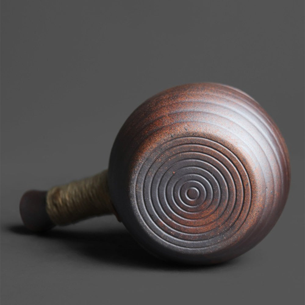 Side view of Japanese teapot with wooden lid and hemp rope handles.