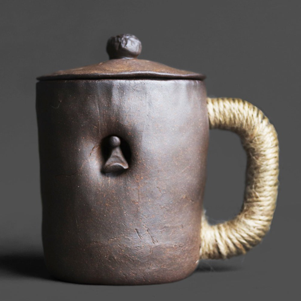 Handcrafted coarse pottery zen tea cup with lid showing textured surface and natural hemp handle