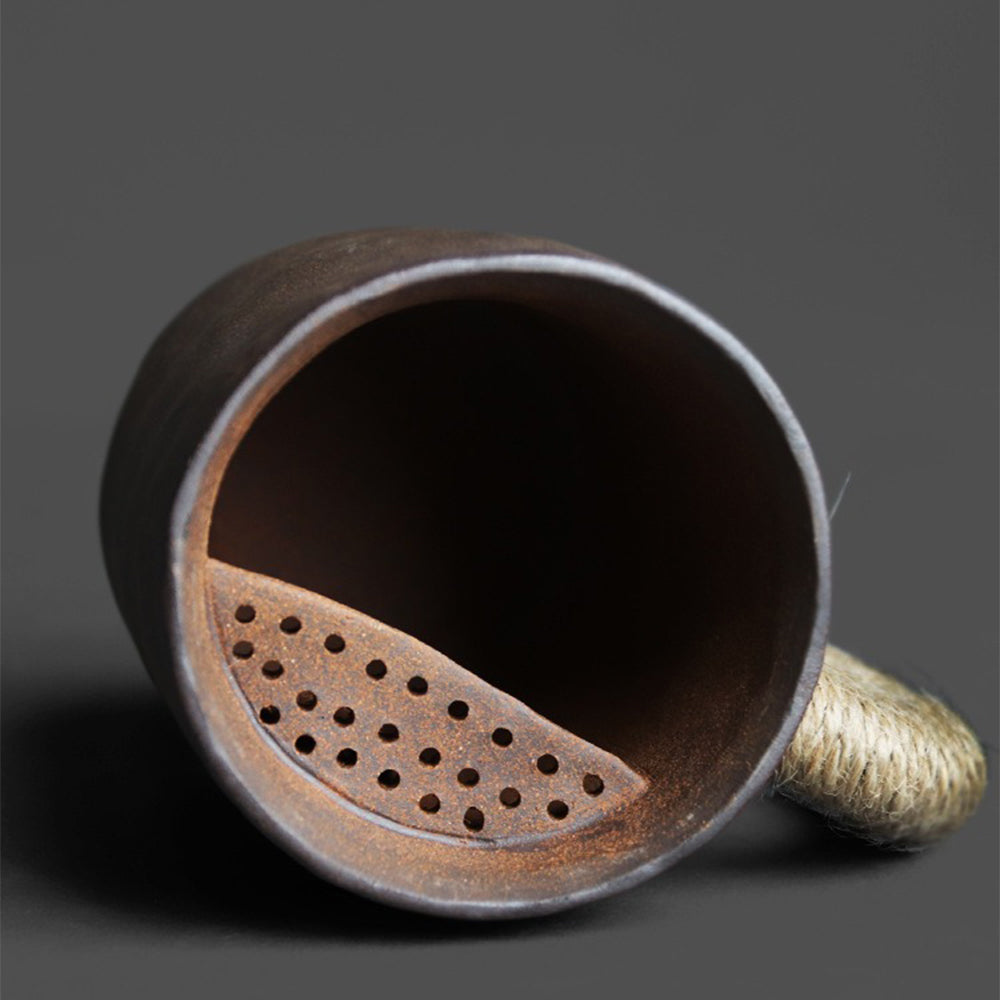 Handcrafted coarse pottery zen tea cup with lid showing textured surface and natural hemp handle