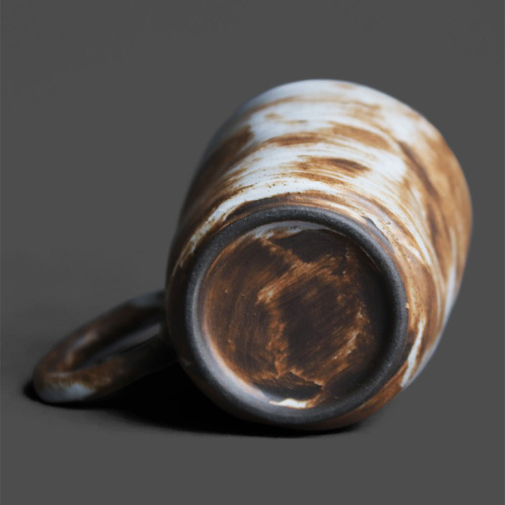 A close-up of a coarse textured ceramic mug with vintage glaze, perfect for tea or coffee.
