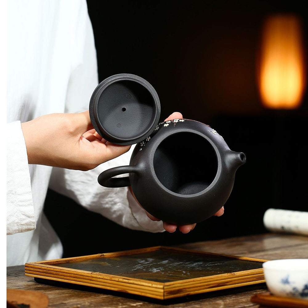 Close-up of the intricate plum blossom pattern on the body of the Yixing teapot, emphasizing its artistic details.