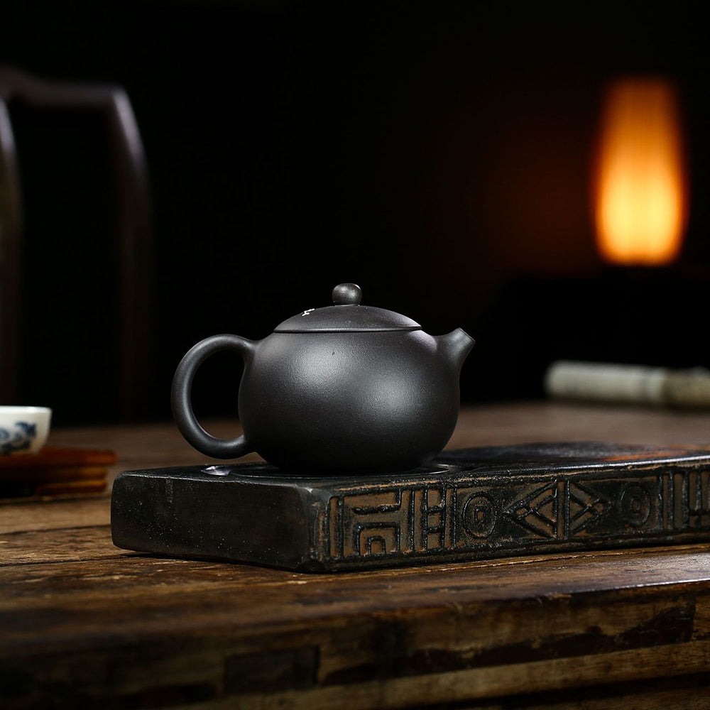 Plum Blossom Yixing Black Clay Teapot from a side view, showcasing its elegant design and craftsmanship.
