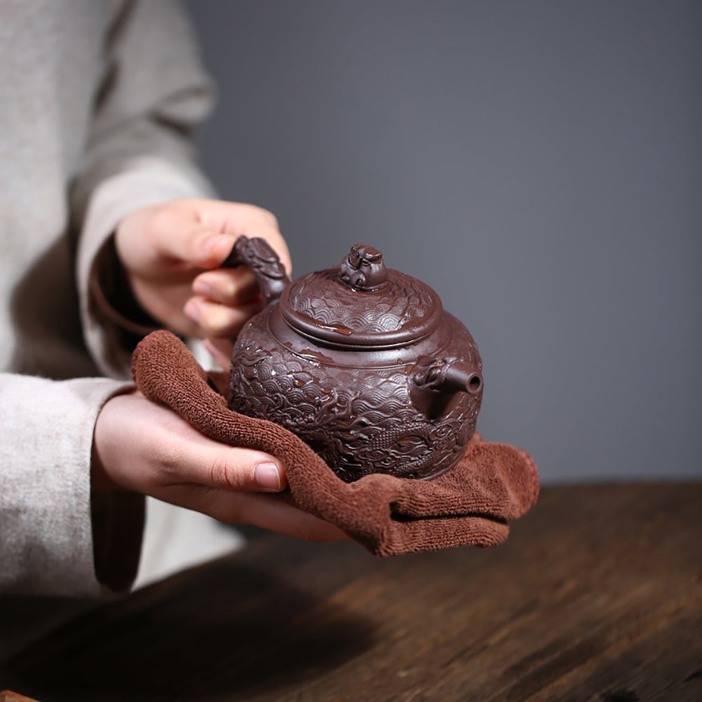 Close-up of embossed dragon and auspicious cloud patterns on purple clay teapot