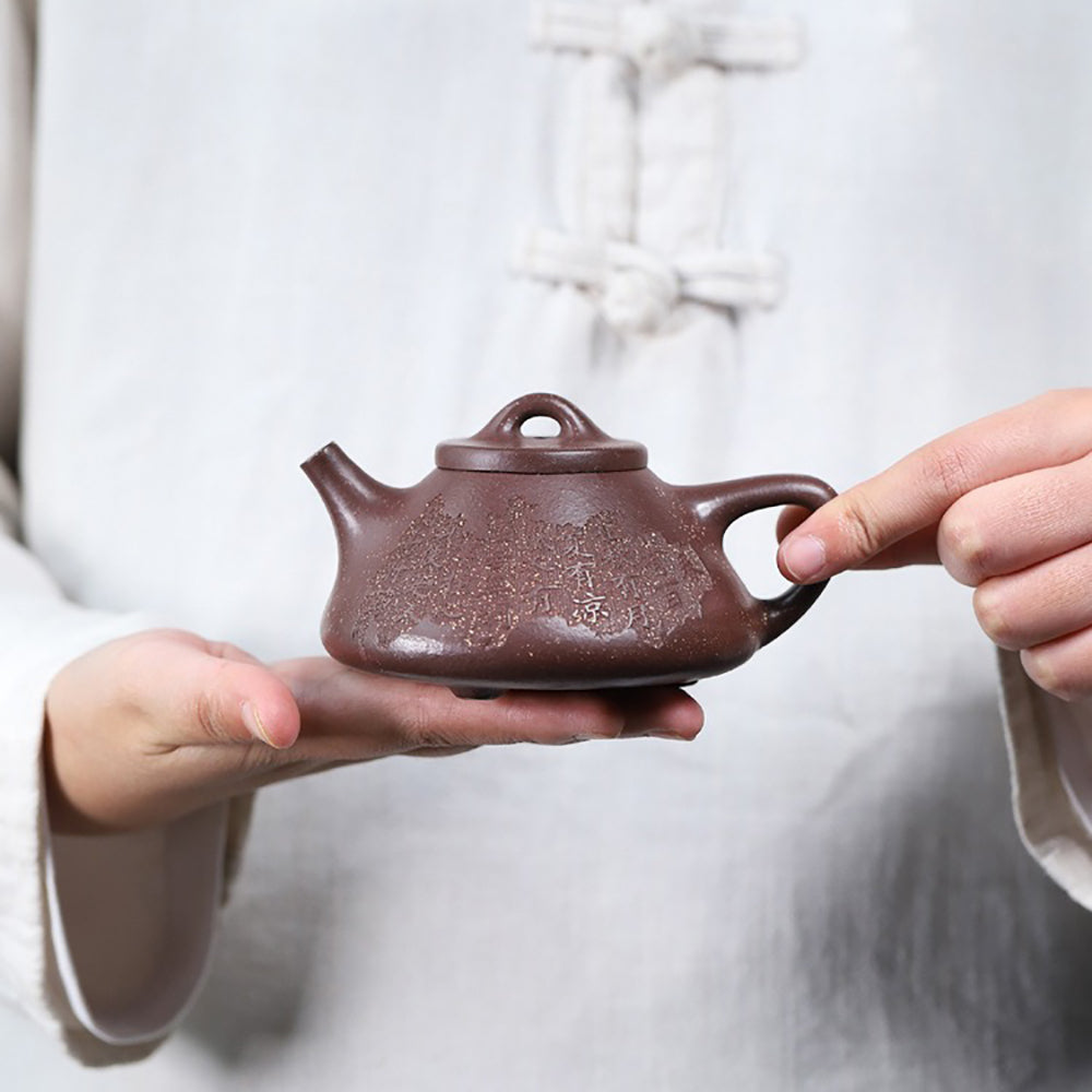 Side angle of the purple clay teapot with a smooth finish, demonstrating its unique triangular shape.