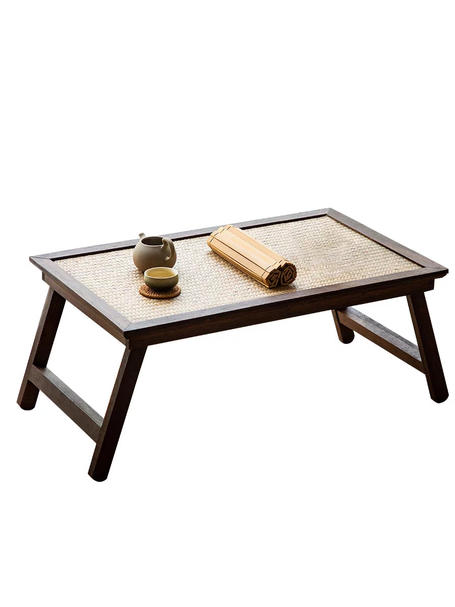 Elegant foldable rattan tea table set up for a tea ceremony in a cozy living room.