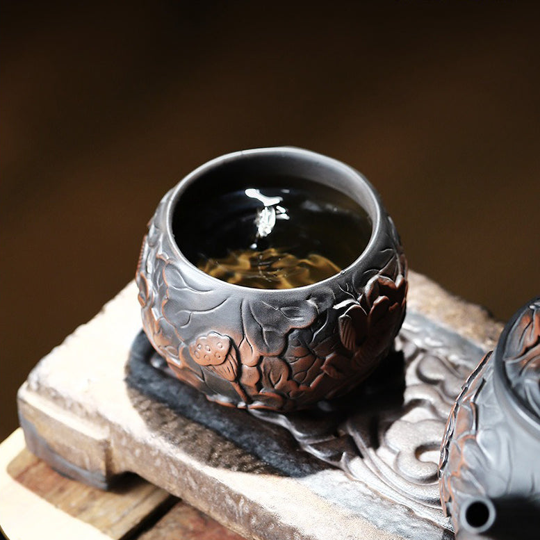 Side view of the black pottery tea cup, showcasing its ergonomic grip and smooth edge.