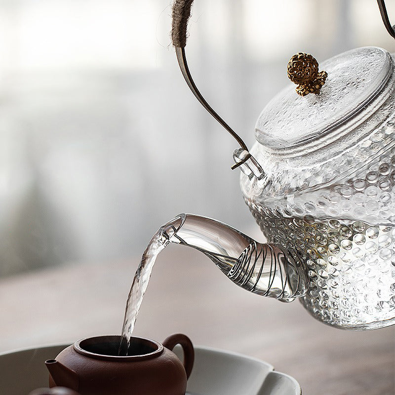 Close-up of brewing tea in a large capacity glass teapot, highlighting the tea leaves.