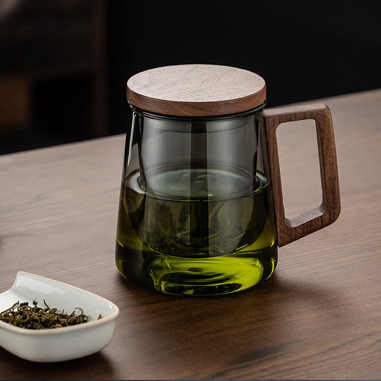 Hand holding a glass tea cup with infuser, showing its elegant design